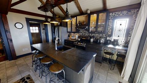 Fully equipped kitchen inside Pedestal House vacation rental at Snowshoe, with a large island, modern appliances, and rustic finishes