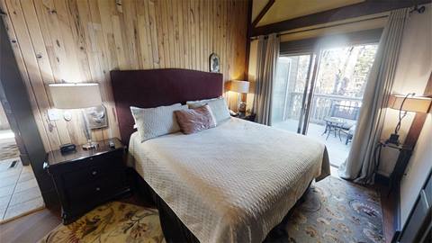 Cozy bedroom in Pedestal House vacation rental with wood paneling, king bed, and access to a private balcony at Snowshoe mountain