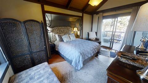 Elegant bedroom in Pedestal House vacation rental at Snowshoe with plush bedding, decorative accents, and mountain facing balcony access