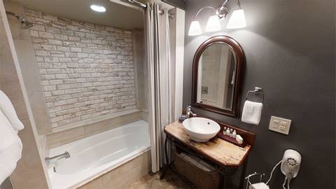 Bathroom in Pedestal House vacation rental featuring a soaking tub, wooden vanity, and soft lighting