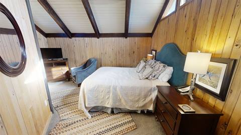 Bedroom in Pedestal House vacation rental with sloped ceilings, a plush bed, and cozy mountain lodge charm