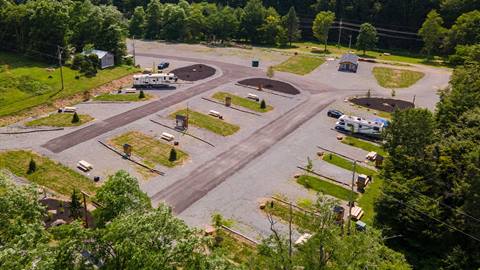 Aerial view of Snowshoe Campground showing multiple rv parking pads, picnic areas, and drive through access bordered by forested hills