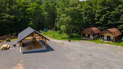 Open air pavilion and two small guest cabins at Snowshoe Campground, offering shaded dining and cozy cabin lodging near the woods
