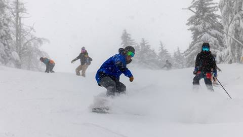 Group skiing and snowboarding in fresh powder snow at Snowshoe Mountain