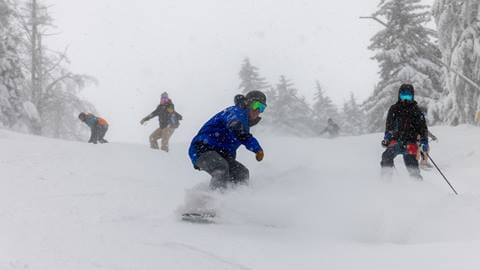 Group skiing and snowboarding in fresh powder snow at Snowshoe Mountain