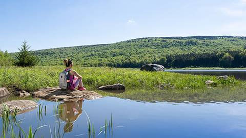 Woman sitting by a lake looking out into the mountains