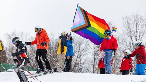 Skiers carry a Pride flag
